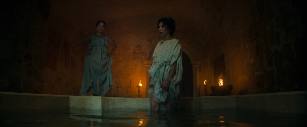 a roman woman of pomeii stands in bath water looking concerned